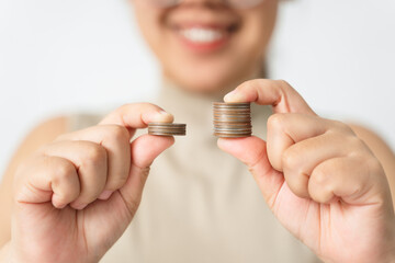 Hands compare two piles of coins of different sizes.