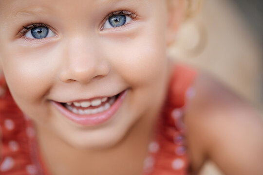 The look of a child with blue eyes is sincere and joyful. Close-up portrait of a happy child with clear positive eyes and a smile.