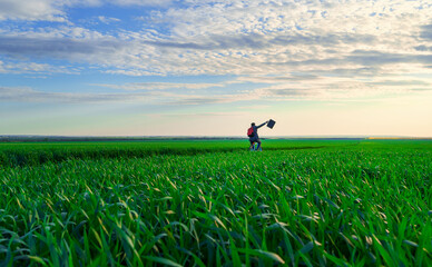a businessman rides a bicycle with a backpack and a briefcase on a green grassy field, dressed in a business suit, beautiful nature in spring, freelance business concept