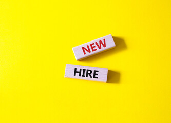 New hire symbol. Wooden blocks with words New hire. Beautiful yellow background. Business and New hire concept. Copy space.