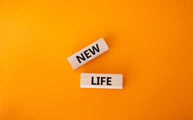 New life symbol. Wooden blocks with words New life. Beautiful orange background. Business and New...