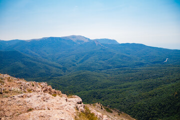 Naklejka premium Mountain landscape in the warm season. Mountains and hills covered with forest, and blue sky. Beauty is in nature.