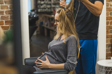 Pregnant woman at hairdresser salon. Soon-to-be mother young adult caucasian woman sitting on...