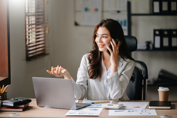 Happy asian business woman have the joy of talking on the smartphone, tablet and laptopon the modern office ..