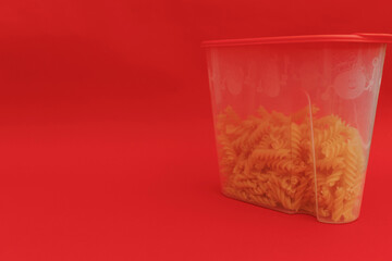 Red jar with macaroni on red background, monochrome