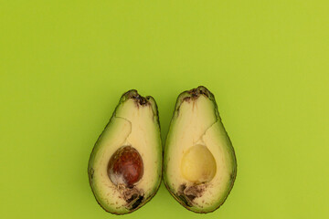 Spoiled avocado on green background, monochrome