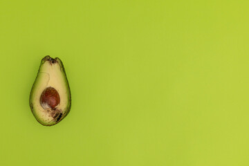 Spoiled avocado on green background, monochrome