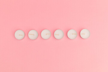 Small candles with wax on a pink background