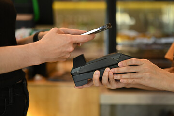 Cropped shot of female customer holding phone and scanning qr code, make contactless mobile payment...