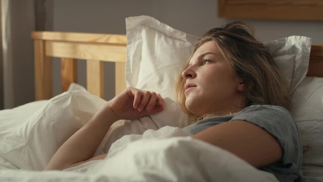 Focus caucasian woman lying in bed and looking away. Shot with RED helium camera in 8K.