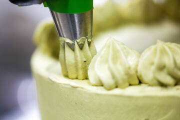 cake chef designer using pistachio cream filling on layered frosted chocolate green cake at kitchen lab