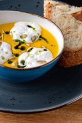 Hot Pumpkin cream soup with coconut espuma and bread on a wooden table. Healthy food