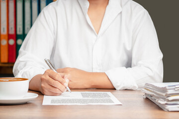 Businessman in a white shirt signing a lease contract or agreement while sitting at the table in...