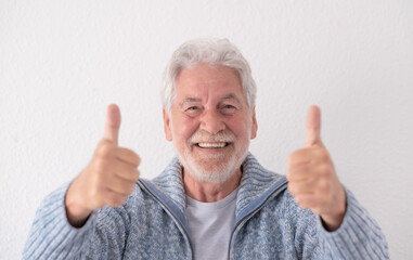 Front view of smiling happy senior grandfather looking at camera with thumbs up expressing positive...