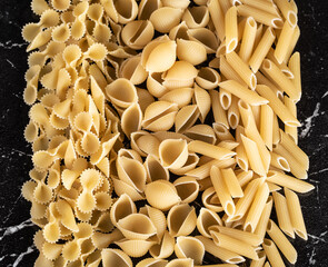 Pasta, spaghetti, capellini, linguini, Fettuccine, Tagliatelle, Papardelle, Fusilli, Aneli, cannelloni, Penne, tortilloni, on the kitchen marble table. top view