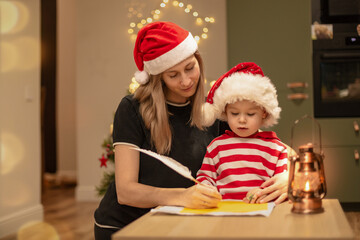 mom write wish list to santa on christmas eve together with son, enjoy christmas at home with happy...