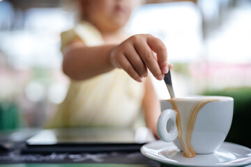 The child's hand stirs the coffee and pours the foam close-up, macro.