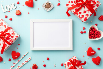 Valentine's Day concept. Top view photo of white photo frame gift boxes heart shaped candles candies inscription love straws plate with sprinkles on isolated pastel blue background with empty space