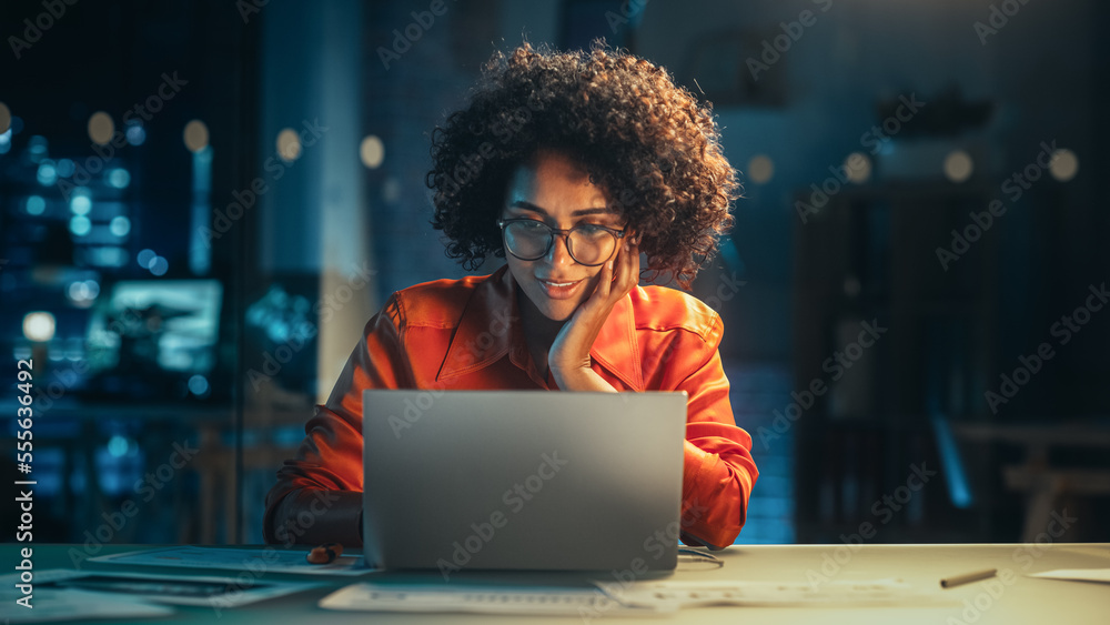 Poster portrait of a happy successful businesswoman using laptop computer in creative agency in the evening
