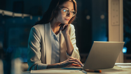 Close Up Portrait of a Young Accountant Working in the Office Late in the Evening. Positive Female Using Laptop Computer, Preparing Job Assignment and Corporate Report for Finance Director.
