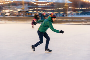 Male in speed demonstrates his skills of skating, has fun on ring, feels sure and confident on ice, spends free time outdoor, enjoys winter vacations, being photographed in movement