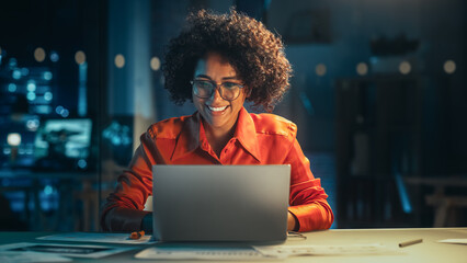 Beautiful Multiethnic Brazilian Female Working on Laptop Computer Late at Night. Young Creative Manager Having Fun in the Office, Chatting with Friends, Laughing and Feeling Happy.