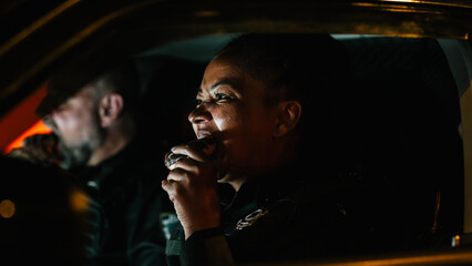 Portrait of Two Police Patrol Officers Sitting in the Car Eating, Watching Over the Streets At...