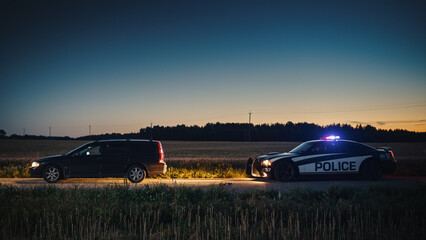 Speeding Driver Gets Pulled Over By Police Patrolling Car During Sunset. Wide Shot of the Two Cars...