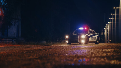 Low Angle Shot of a Stopped Police Car with Lights and Siren on During a Misty Night. Patrolling Vehicle on Stand by, Waiting for Orders to Start Pursuing Suspects. Police Enforcement