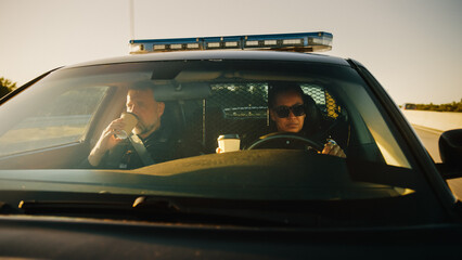 Point of View: Two Police Officers Driving Traffic Patrol Car, Drink Coffee, Chat, Joke Around, Ready to Fight Crime. Police Patroling, Officers of the Law Maintain Public Order, Safety, Investigation © Gorodenkoff