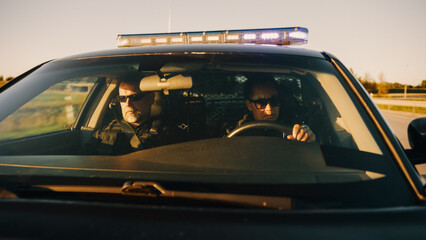 Point of View: Two Police Officers Driving Traffic Patrol Car, Ready to Fight Crime. Squad Car Police Patroling, Crusing, Officers of the Law Maintain Public Order, Safety © Gorodenkoff
