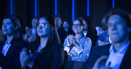 Audience Full of Business People Clapping in Dark Conference Hall During an Inspiring Keynote...