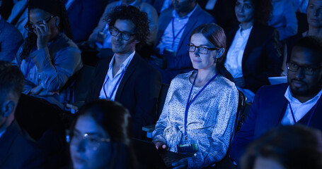 Beautiful Woman Sitting in Crowded Audience at a Business Conference. Female Delegate Using Laptop...