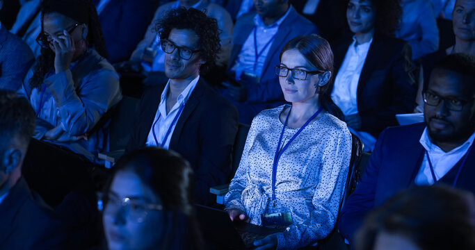 Beautiful Woman Sitting in Crowded Audience at a Business Conference. Female Delegate Using Laptop to Take Notes. Manager Watching Inspirational Entrepreneurship Presentation About Developing Markets.