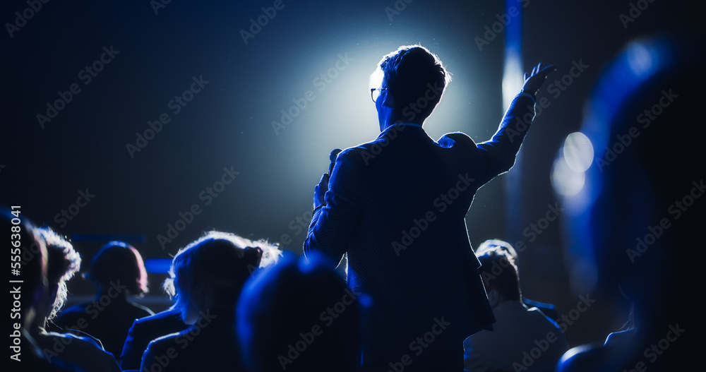 Fototapete backview of a stylish young businessman in a dark crowded auditorium at a startup summit. young man 