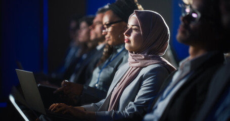 Arab Female Sitting in a Dark Crowded Auditorium at a Human Rights Conference. Young Muslim Woman...