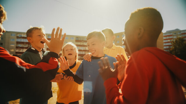 Neighborhood Kids Playing Soccer In Eastern European Backyard. Young Football Players Dribbling, Passing Ball, Scoring A Goal. Boys And Girls Celebrate The Victory. Wide Shot.