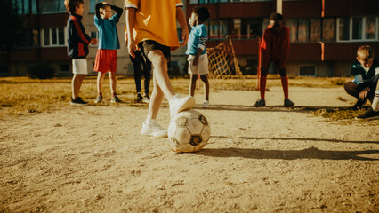 Cute Girl Playing Keepie Uppies with a Soccer Ball Together with Multiethnic Kids in the Neighborhood. Happy Boys and Girls Juggling the Ball in the Air. Concept of Sports, Childhood, Friendship. © Gorodenkoff