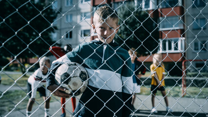 Portrait of a Cute Boy Holding a Soccer Ball on an Outdoors Field in the Neighborhood. Young...