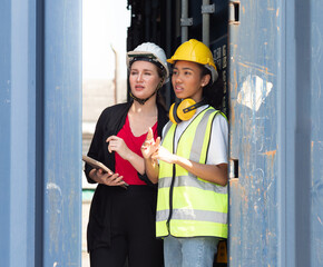 Diverse people enjoy working together at container yard. Industrial engineer woman and female foreman wear safety hardhat are looking forward at cargo distribution. Diversity business people concept