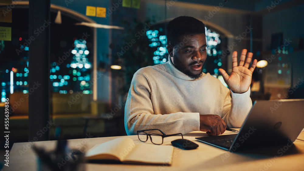 Aufkleber young handsome black man is having a lively discussion on video call on laptop computer in office in