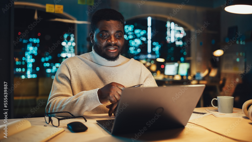 Poster portrait of a handsome black project manager making a video call on laptop computer in an evening of