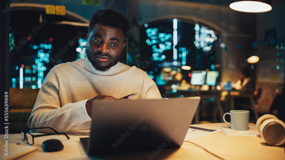 Leinwandbilder handsome black project manager making a video call on laptop computer in an evening office environme