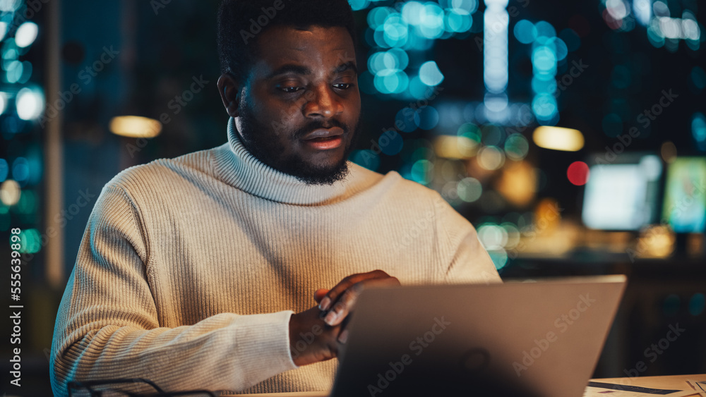 Leinwandbilder handsome black project manager making a video call on laptop computer in an evening office environme