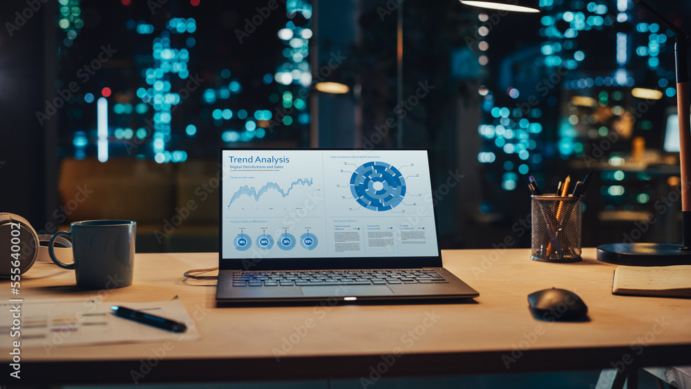 Poster laptop standing on a desk with sales statistics and data chart displayed on screen. table with compu