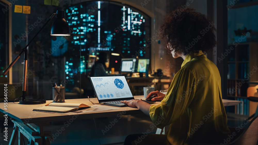 Poster creative multiethnic female working on laptop computer with a sales statistics and chart displayed o