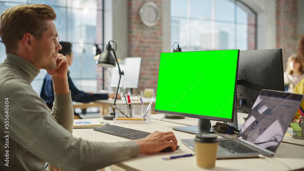 Poster Portrait of White Creative Young Man Working on Green Screen Computer During the Day in Modern Busy Office. Project Manager Smiling While Using Desktop Computer.
