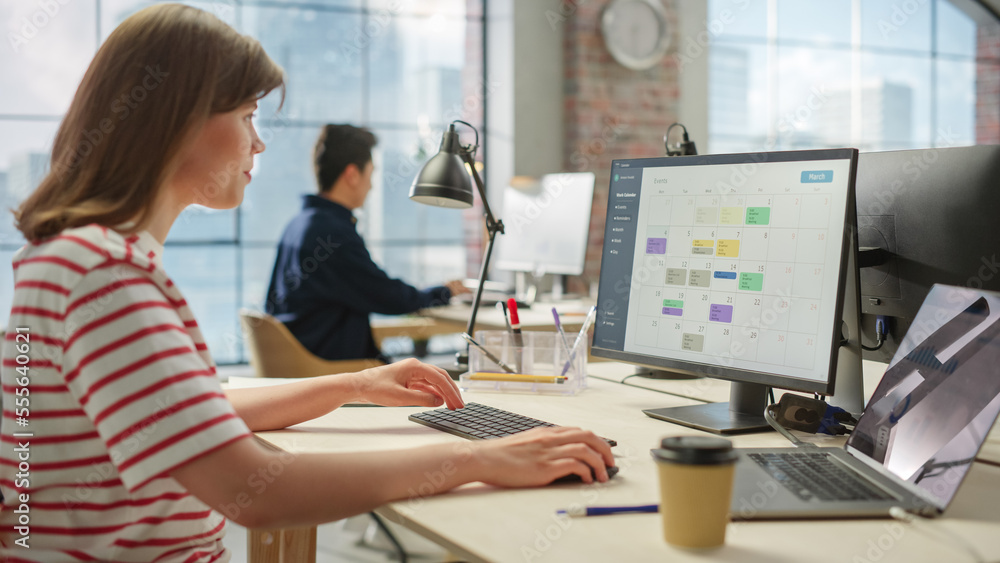 Poster portrait of caucasian creative young woman working on a calender software on a desktop computer in b