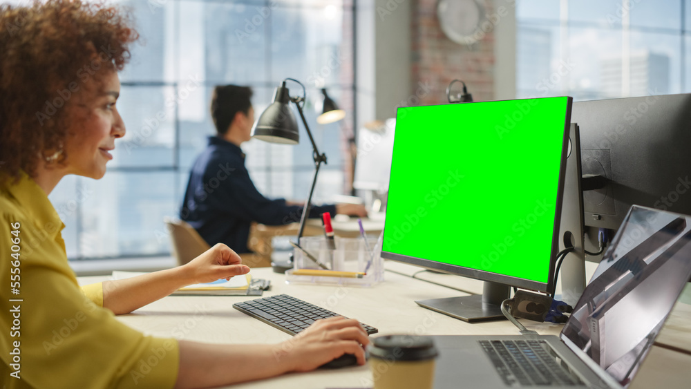 Poster portrait of a young creative biracial woman working on a computer with green screen display in moder