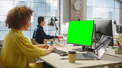 Employees Smiling While Working on Computers in Busy Modern Bright Office. Biracial Woman Designing Using Green Screen. Male Employee Working in the Background. - Powered by Adobe